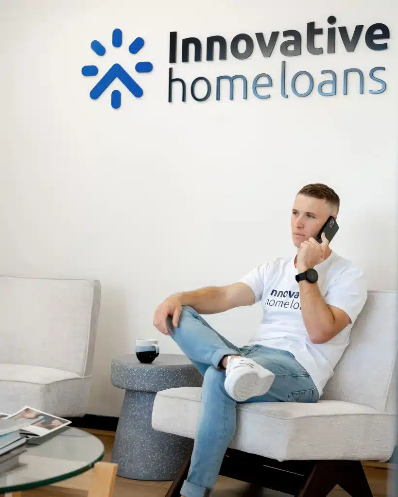 A man sitting on a chair in front of an innovative home loans sign.