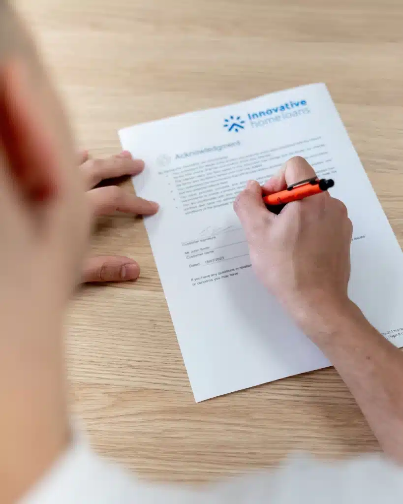A man signing a paper with a red pen.